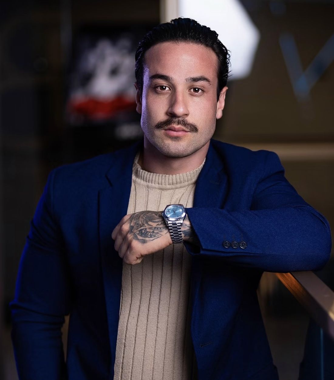 Patrick Biazotto de blazer azul e suéter bege, mostrando o relógio